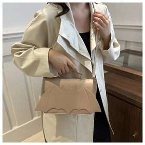 Chic beige bat-shaped crossbody bag with wing detail shown in a modern interior setting