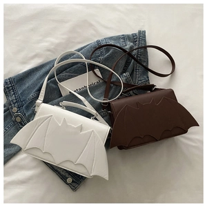 Detalle de bolsos bandolera con alas de murciélago sobre una chaqueta vaquera azul