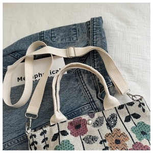 Detail view of the floral jacquard fabric and silver metal hardware of this canvas tote bag