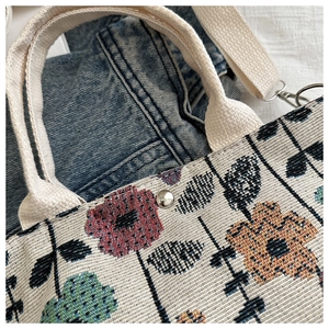 Macro detail of retro jacquard fabric with floral embroidery and canvas handle strap