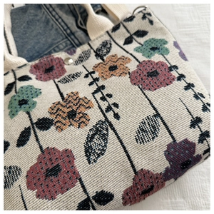 Detail of floral tapestry tote bag with metal buckle and strawberry pattern texture