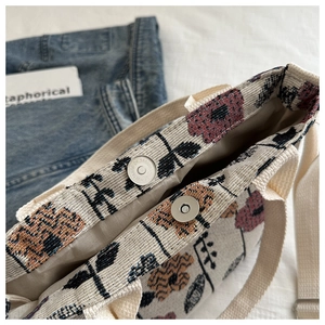 Detailed close-up of woven floral tote bag showing magnetic clasp and canvas strap