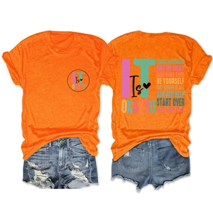Detail of vibrant orange crew neck tee with inspirational text and ripped denim shorts
