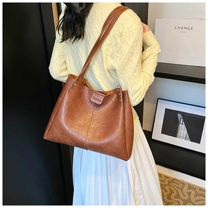 Detail of vintage brown tote bag with metal rivets and fashion label on leather texture