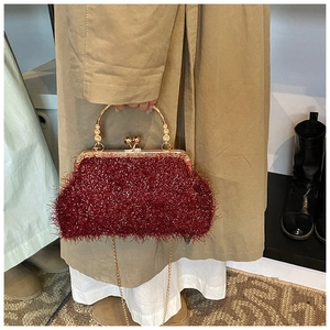 Detail of red plush evening bag featuring a vintage gold clasp and elegant chain strap