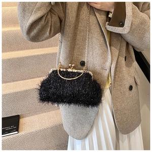 Detail of elegant black evening bag with glossy fringe and gold handle