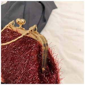 Close-up of retro burgundy fringed clutch with vintage engraved gold metal clasp