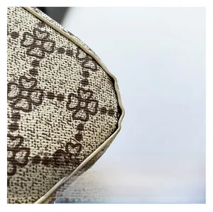 Nahaufnahme des beigen Kleeblattmusters und der Premium-Nähte der Halbmond-Tasche