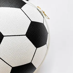 Detail der fußballförmigen Handtasche aus schwarz-weißem Leder mit goldenem Reißverschluss