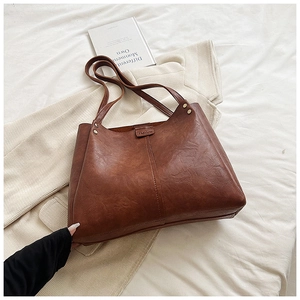 Detail view of brown leather tote bag showing fine texture and FASHION embossed logo