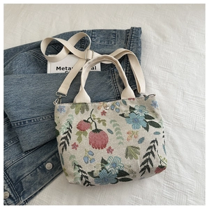 Chic canvas crossbody bag with floral embroidery on denim jacket, stylish autumn handbag