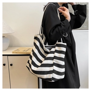 Detail shot of a striped canvas tote bag worn by a model in a modern interior setting