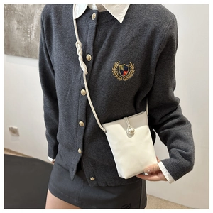 Dettaglio della mini borsa porta cellulare in pelle bianca con bottone a perla