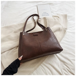 Close-up of retro dark brown PU tote bag with wrinkled texture and fashion tag detail