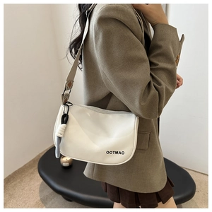 Detailed shot of white half-moon crossbody bag with ethnic wide strap and OOTMAO logo