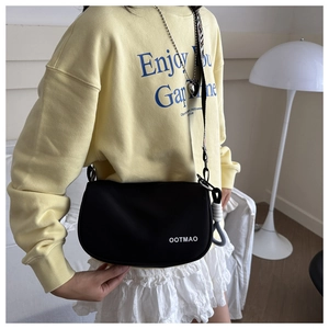 Detail of black canvas dumpling bag with white OOTMAO lettering and wide fabric strap