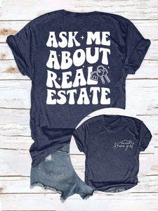 Détail de l'imprimé Ask Me About Real Estate sur un t-shirt bleu marine court