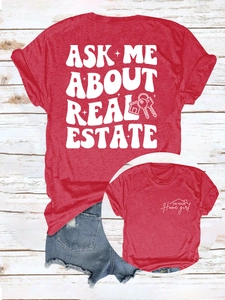 Détail du t-shirt rouge à slogan immobilier et short en jean sur sol en bois