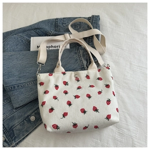 Corduroy crossbody tote bag with strawberry prints on denim background