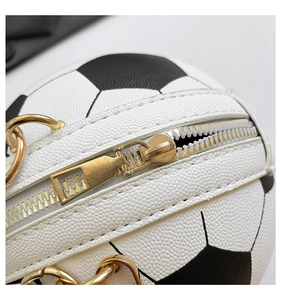 Macro shot of football-shaped bag detailing golden zipper and black-white faux leather texture