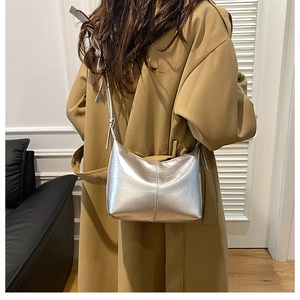 Detail of silver metallic hobo bag with cracked faux leather texture on khaki trench coat