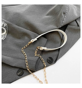 Detail of white leather handle with gold chain strap on a grey textured suit fabric