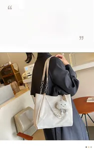 Détail du sac cabas en similicuir crème avec chaîne de perles et charm nuage pelucheux
