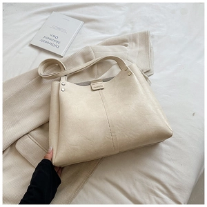Close-up of cream white tote bag with vintage cracked leather texture and metal studs