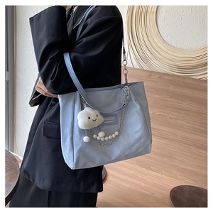 Détail d'un grand sac cabas bleu clair avec chaîne de perles et charm nuage doux