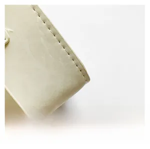 Close-up of beige leather bag corner showing precise stitching and premium texture