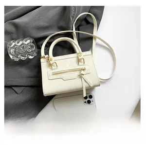 Detail of cream marble-textured crossbody bag with gold hardware and smooth handle