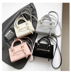 Detail shot of mini crossbody bags in white, gray, pink, and black with tassel zippers
