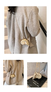 Detail of a golden metallic shell-shaped mini bag with chain strap on a grey wool coat