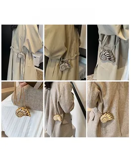 Detail shots of snail-shaped shell evening bag with chain strap in gold and silver