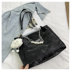 Détail d'un cabas noir avec chaîne argentée et breloque nuage sur une veste en jean