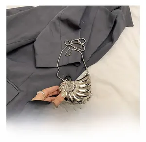 Detail of silver metallic seashell clutch with spiral texture and slim snake chain strap