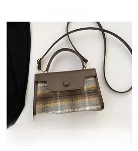 Detail of vintage plaid wool handbag with brown leather handle and circular metal clasp