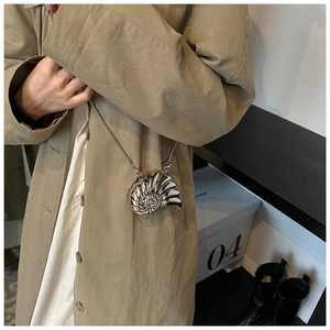 Close-up of metallic shell-shaped crossbody bag with polished silver finish and chain