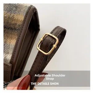 Detail of adjustable leather strap with gold buckle on plaid wool shoulder bag