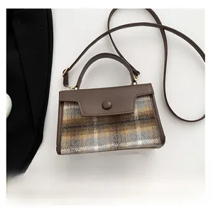 Detail view of mini plaid tweed and brown leather handbag shown with phone for scale