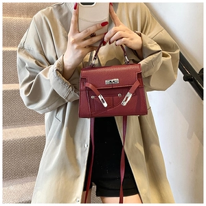 Close-up of deep red lychee grain leather handbag with silver metallic turn-lock detail