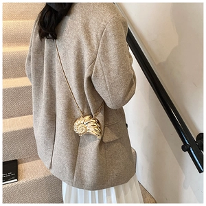 Detail of a golden metal conch-shaped mini shell bag with elegant chain strap for women
