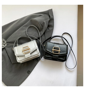 Flat lay of small crossbody bags in black and silver with gold buckles on a suit jacket