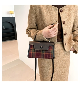 Close-up of vintage red and green tartan wool handbag with black leather flap and shoulder strap