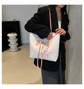 Détail d'un sac cabas blanc avec motifs embossés et breloque pompon en fourrure rose