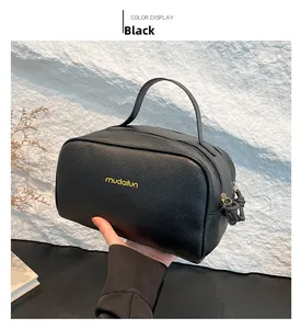 Detail of black pebbled faux leather cosmetic bag with gold zipper and top handle