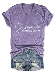 Dettaglio della maglietta viola con scollo a V e stampa e pantaloncini di jeans strappati