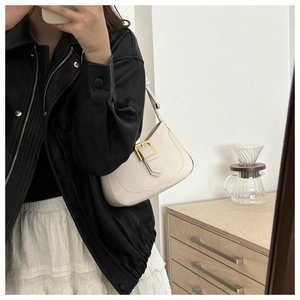 Sac croissant chic en cuir crème porté avec une veste en cuir et une jupe blanche