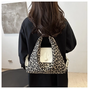 Leopard print tote bag with white leather flap shown on a model's shoulder in casual style