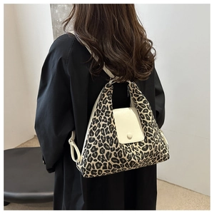 Detail view of stylish leopard print tote bag with white flap on model's shoulder